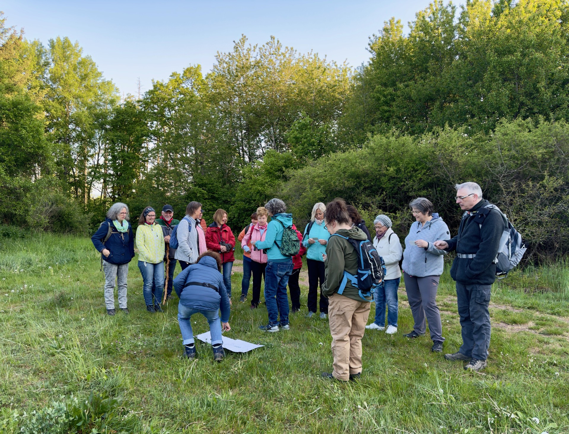 Eine Wandergruppe steht am frühen Morgen auf einer Wiese bei der Morgentauwanderung in Heimbach 
