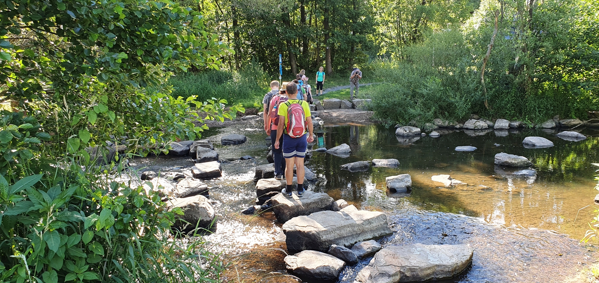 Eine Wandergruppe läuft über die Trittsteine über die Nahe am Nahesteig