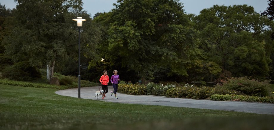 Zwei Frauen joggen an einer Laterne vorbei