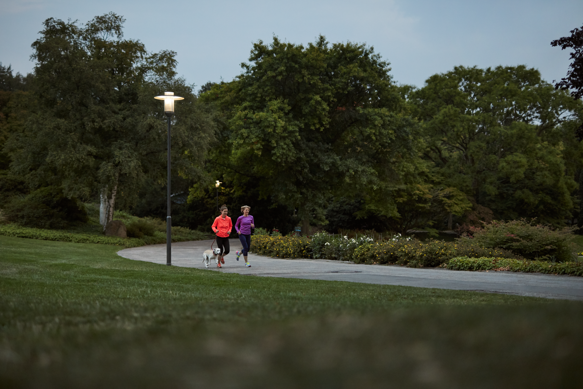 Zwei Frauen joggen an einer Laterne vorbei
