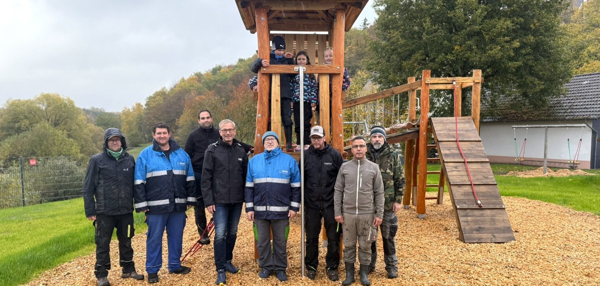 Helfer aus Berglangenbach und Thomas Johann von der OIE stehen vor den Spielgeräten auf dem neuen Spielplatz in Berglangenbach.