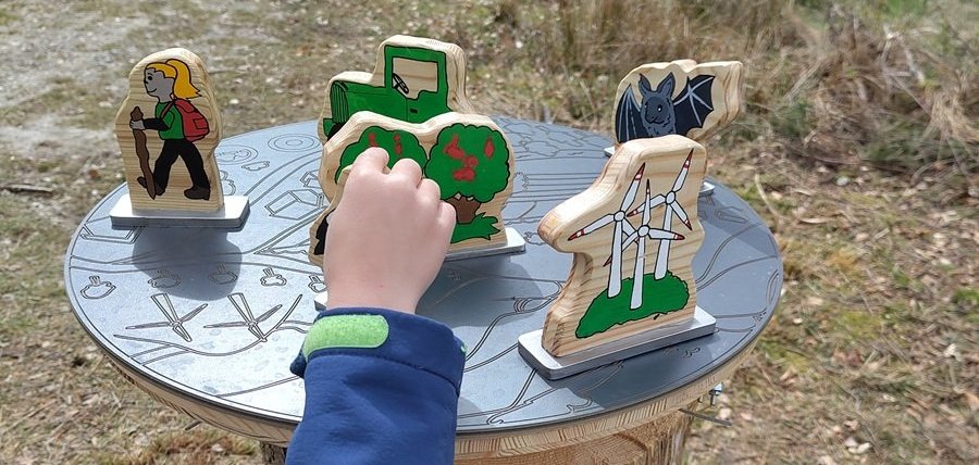 Naturvielfaltspfad am Erbeskopf - Spielfiguren für Kinder auf einer Platte, die an einem Holzklotz befestigt ist.
