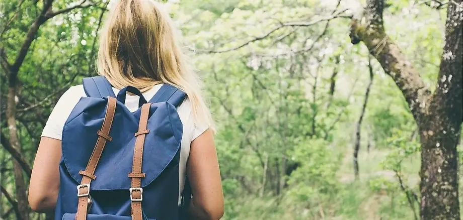 Frau mit Rucksack wandert auf einem Waldweg Frau mit Rucksack wandert auf einem Waldweg