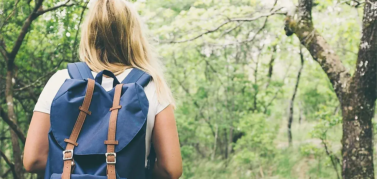 Frau mit Rucksack wandert auf einem Waldweg