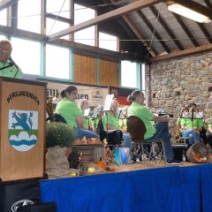 Musikverein Germania Ruschberg in Markthalle am Bauernmarkt in Berglangenbach. Bürgermeister Alsfasser steht am Rednerpult